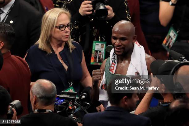 Floyd Mayweather Jr. Celebrates after his TKO of Conor McGregor in their super welterweight boxing match alongside Kelly Swanson of Swanson...
