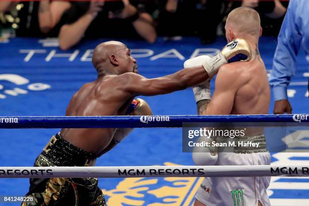 Floyd Mayweather Jr. Throws a punch at Conor McGregor during their super welterweight boxing match on August 26, 2017 at T-Mobile Arena in Las Vegas,...