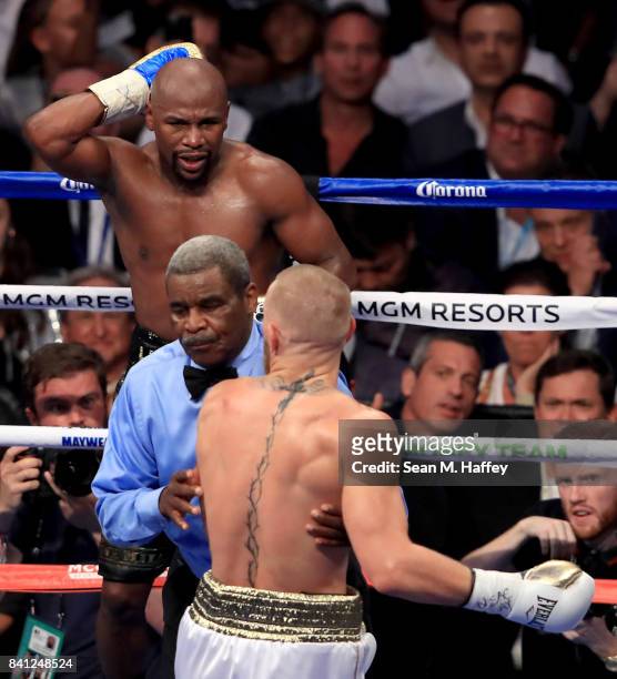 Floyd Mayweather Jr. Holds the back of his head as referee Robert Byrd pushes Conor McGregor away during their super welterweight boxing match on...