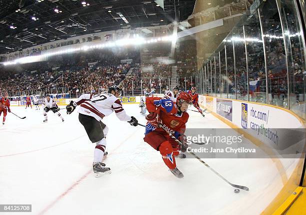 Edgars Lipsbergs of Latvia tries to get the puck from Alexander Komaristy of Russia at the Civic Centre on December 26, 2008 in Ottawa, Ontario,...