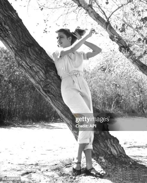 Portrait de l'actrice Grace Kelly se coiffant adossée à un tronc en 1954.