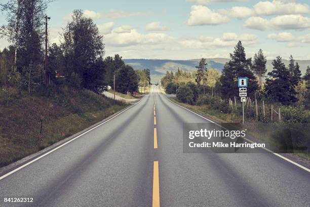 long, straight road through norwegian scenery - long road stockfoto's en -beelden