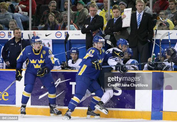 Joonas Nattinen of Finland is checked into the boards by Simon Hjalmarsson of Sweden as Joakim Andersson of Sweden looks on at the Civic Centre on...