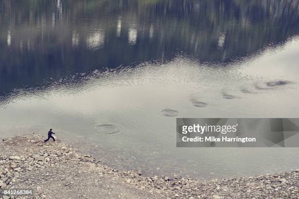 young male skimming stones - throwing fotografías e imágenes de stock