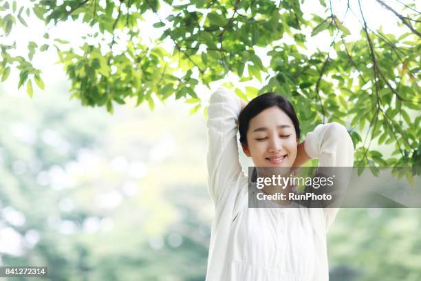 young lady who is closing his eyes and enjoying rest in the park - forest bathing stock pictures, royalty-free photos & images