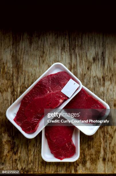 raw beef schnitzels in the box wrapped with food film arranged on the wooden table as an arrow pointer - curly arrow stock pictures, royalty-free photos & images