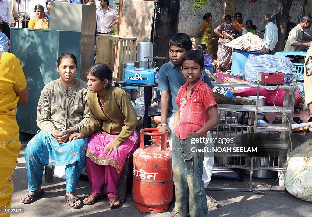 Indian residents sit among their houshol
