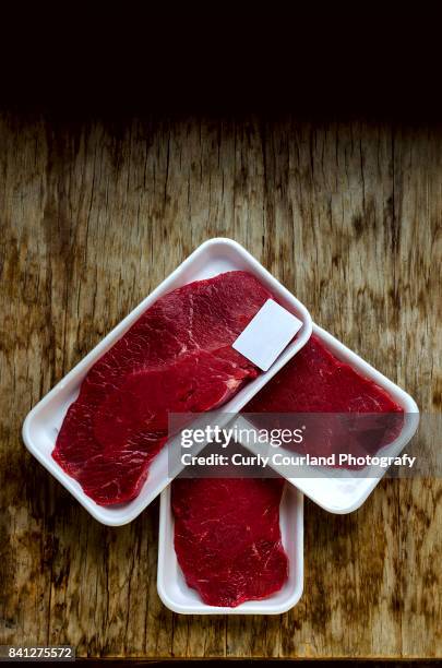 raw beef schnitzels in the box wrapped with food film arranged on the wooden table as an arrow pointer - curly arrow stock pictures, royalty-free photos & images