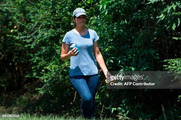 Woman wearing a Center for Toxicology & Environmental Health LLC hat works in a rural residential area after a chemical plant operated by the Arkema...