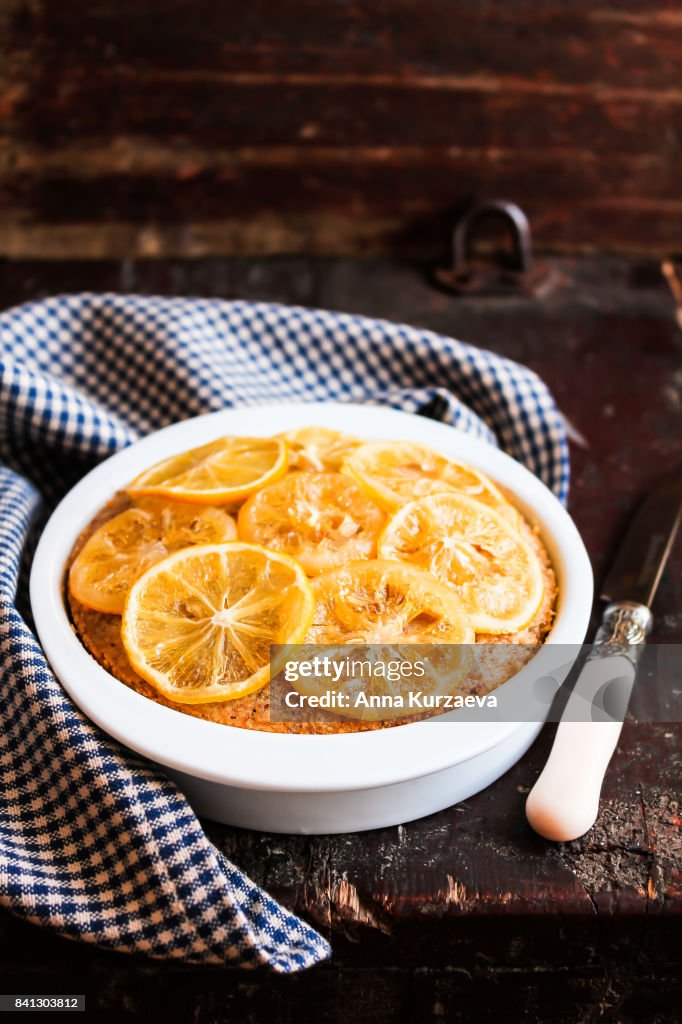 Homemade lemon cake with candied lemon sliced fruit in a bowl on a wooden table, selective focus