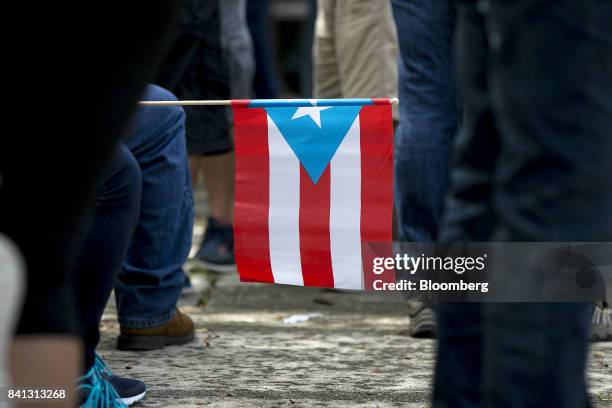 Demonstrator holds a Puerto Rican flag during a union protest against austerity measures in San Juan, Puerto Rico, on Wednesday, Aug. 30, 2017. The...