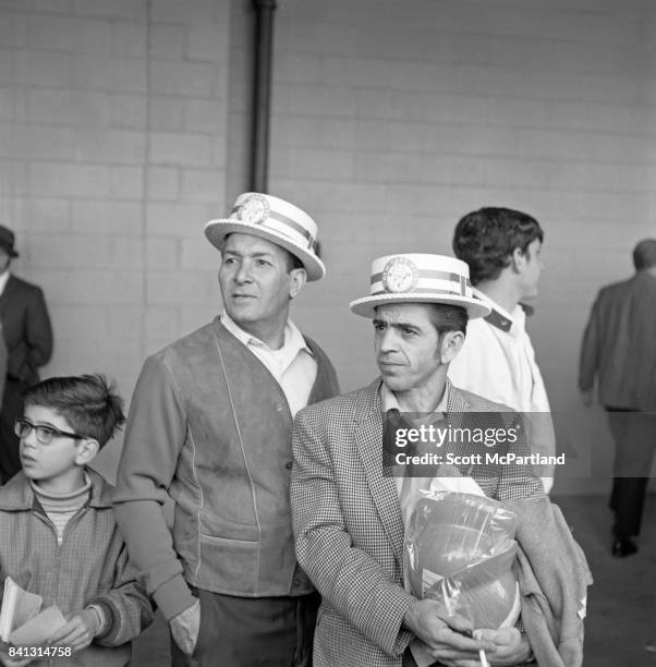 Shea Stadium : 2 middle aged men wearing retro NY Mets hats, stand with a young boy, and watch Game 5 of the World Series from the walkway around the...