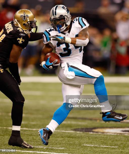 DeAngelo Williams of the Carolina Panthers tries to avoid a tackle by Roman Harper of the New Orleans Saints on December 28, 2008 at the Superdome in...