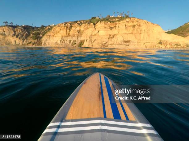 a paddle board glides in the pacific ocean at  black's beach in the la jolla section of san diego, california - san diego pacific beach stock pictures, royalty-free photos & images