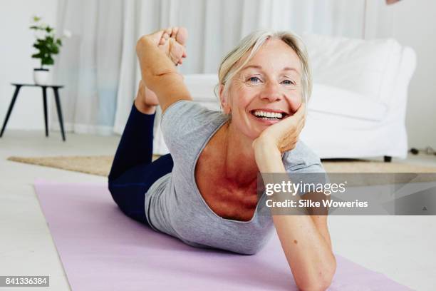 portrait of an content gray haired woman doing yoga at home - fitness or vitality or sport and women fotografías e imágenes de stock