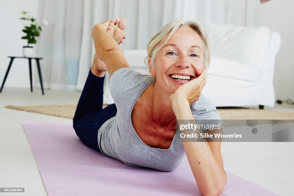 Portrait of an content gray haired woman doing yoga at home