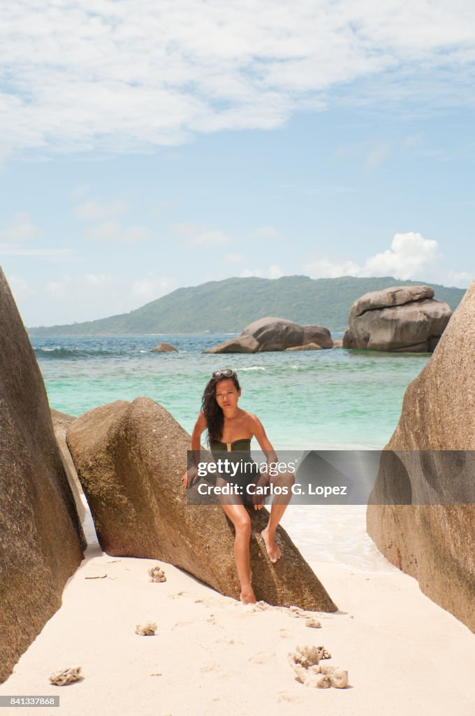 Asian girl in green swimming suit posing on rock