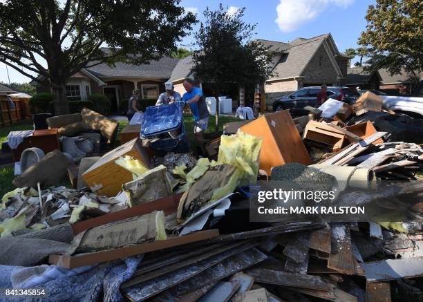 Members of the Olson family remove debris and damaged items from their father's home in the Twin Oaks Estate after Hurricane Harvey caused widespread...