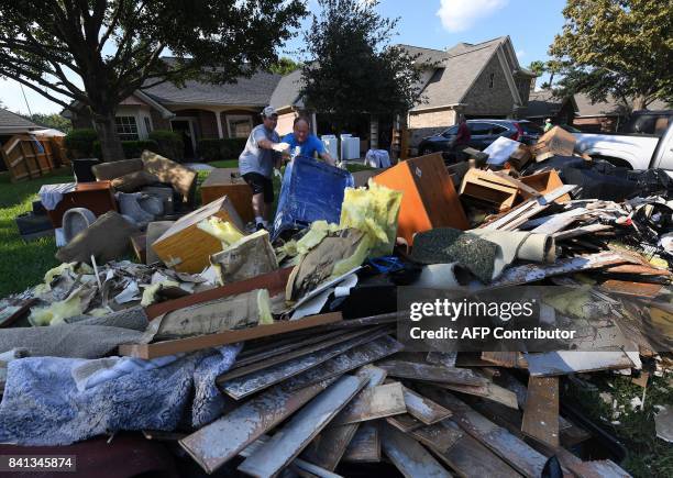 Members of the Olson family remove debris and damaged items from their father's home in the Twin Oaks Estate after Hurricane Harvey caused widespread...