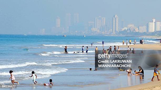 Sri Lankan people enjoy a dip in the sea on a beach in Colombo December 26, 2008. Sri Lanka paid tribute to an estimated 31,000 people killed by the...