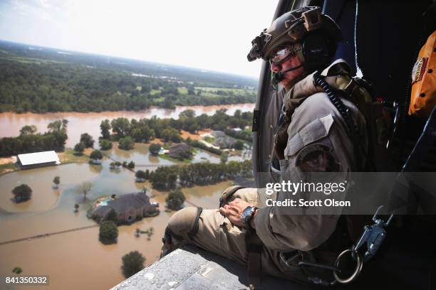 Oscar Peru of U.S. Customs and Border Protection searches for flood victims from a helicopter after torrential rains pounded the area following...