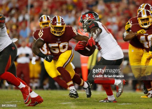 Running back Peyton Barber of the Tampa Bay Buccaneers gets pressure from outside linebacker Martrell Spaight of the Washington Redskins during a...