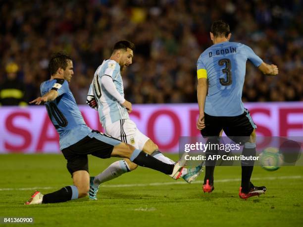 Argentina's Lionel Messi vies for the ball with Uruguay's Alvaro Gonzalez and Diego Godin during the 2018 World Cup football qualifier matchin...