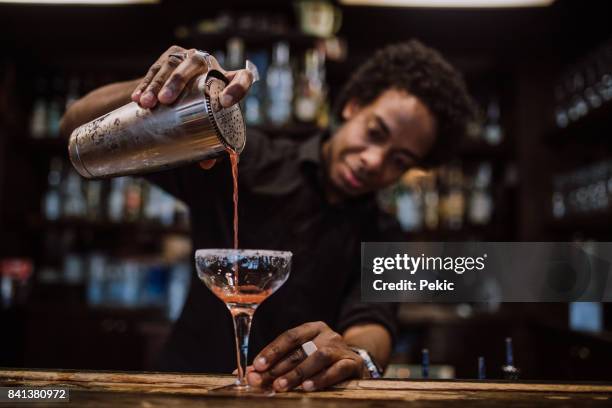 jonge barman gieten cocktails in een cocktailbar - cocktails stockfoto's en -beelden