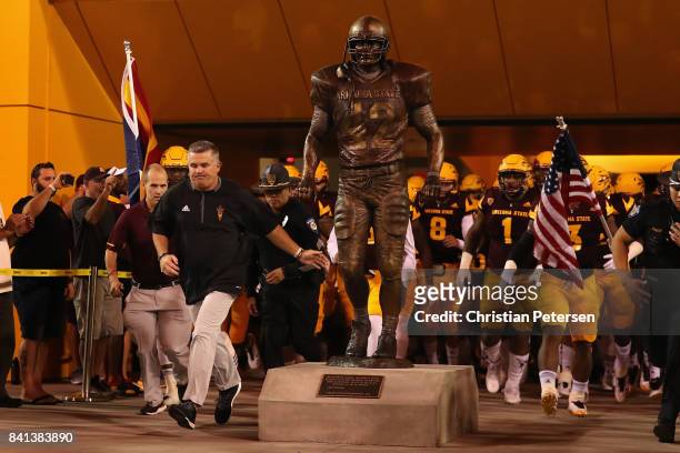 Head coach Todd Graham of the Arizona State Sun Devils touches the new Pat Tillman statue as he leads his team onto the field before the college...