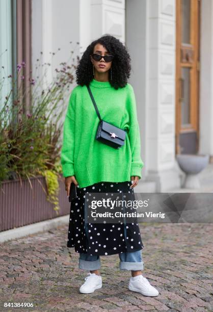 Guest wearing a green knit, skirt over denim jeans, sneaker outside Valerie on August 31, 2017 in Stockholm, Sweden.