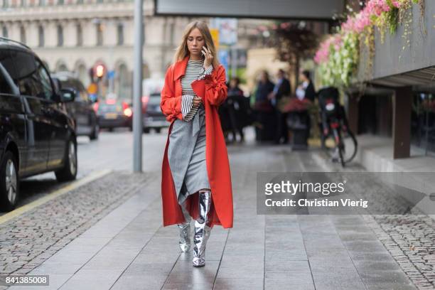 Lisa Olsson wearing striped long shirt, red coat, silver boots, grey skirt outside Valerie on August 31, 2017 in Stockholm, Sweden.