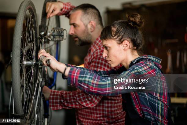 teamwork all over the place - twee collega's fiets repareren - reparatiewerkplaats stockfoto's en -beelden