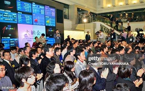 Visitors clap during the the last trading for the year at the Tokyo Stock Exchange in Tokyo on December 30, 2008. Japanese share prices closed the...