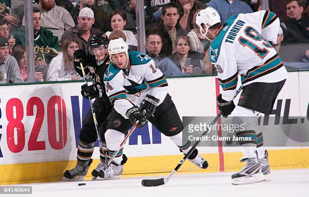 Jonathan Cheechoo and Joe Thornton of the San Jose Sharks try to keep the puck away against Landon Wilson of the Dallas Stars on December 29, 2008 at...