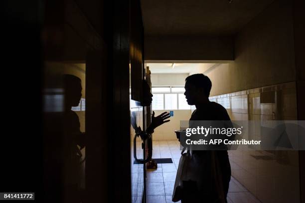 In this picture taken on August 29 a resident in a government housing block gestures while speaking to a Caritas charity worker delivering a food box...