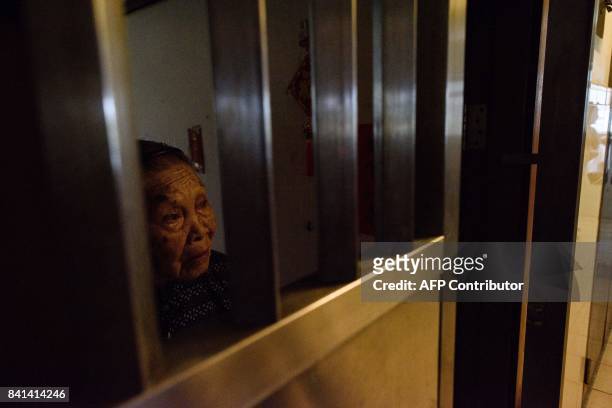 In this picture taken on August 29 an elderly resident stands by the security gate of her government housing block flat entrance as she waits to...