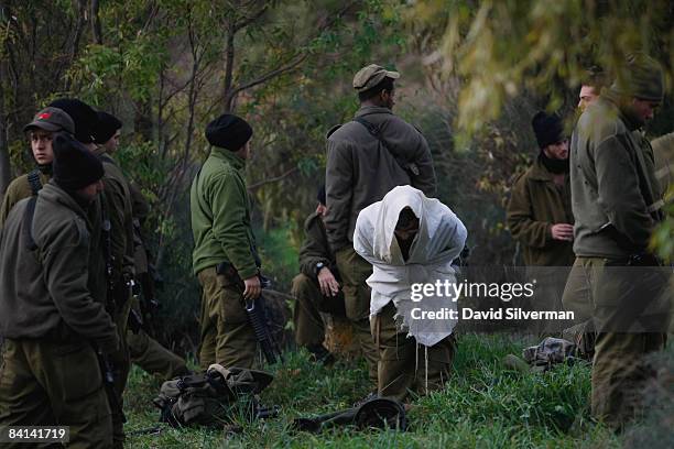 An Israeli soldier is wrapped in a Tallit, a Jewish prayer shawl, as he recites his morning prayers at an advance deployment area on December 30,...