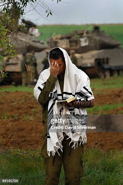 An Israeli soldier is wrapped in a Tallit, a Jewish prayer shawl, as he recites his morning prayers at an advance deployment area on December 30,...