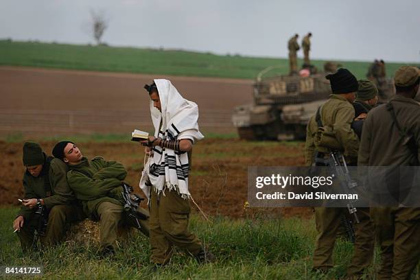 An Israeli soldier is wrapped in a Tallit, a Jewish prayer shawl, as he recites his morning prayers at an advance deployment area on December 30,...