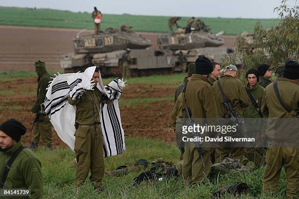 An Israeli soldier wraps himself in a Tallit, a Jewish prayer shawl, to recite his morning prayers at an advance deployment area on December 30, 2008...