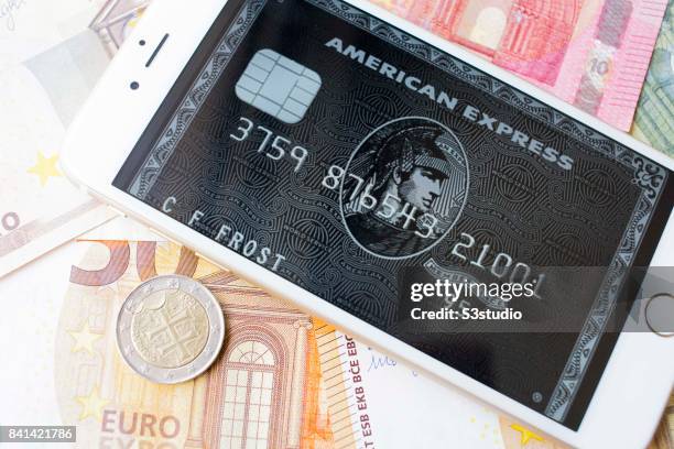 In this Photo Illustration, Euro banknotes and coins with American Express card sample on an iPhone 6s Plus are arranged for a photograph on 30...