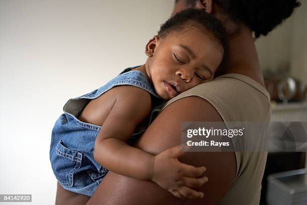 baby asleep on mums shoulder - mother holding baby stockfoto's en -beelden