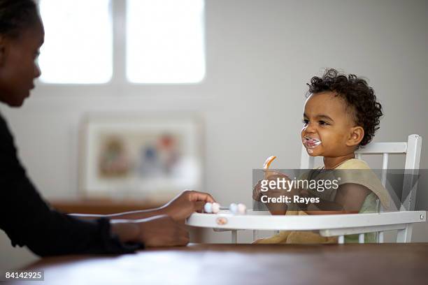 baby feeding himself yoghurt - high chair stock pictures, royalty-free photos & images