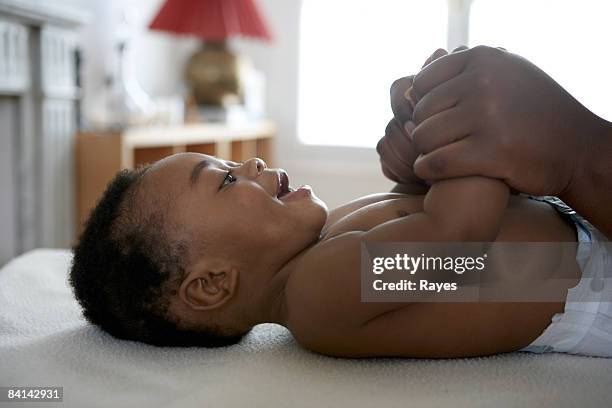 bebê deitado para baixo, segurando suas mãos das mães - kids in diapers - fotografias e filmes do acervo