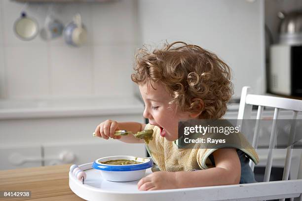 baby boy sitting in high chair feeding himself - boy curly blonde stock pictures, royalty-free photos & images