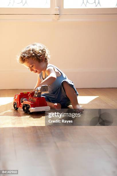 baby boy playing with toy fire engine - wooden floor stockfoto's en -beelden