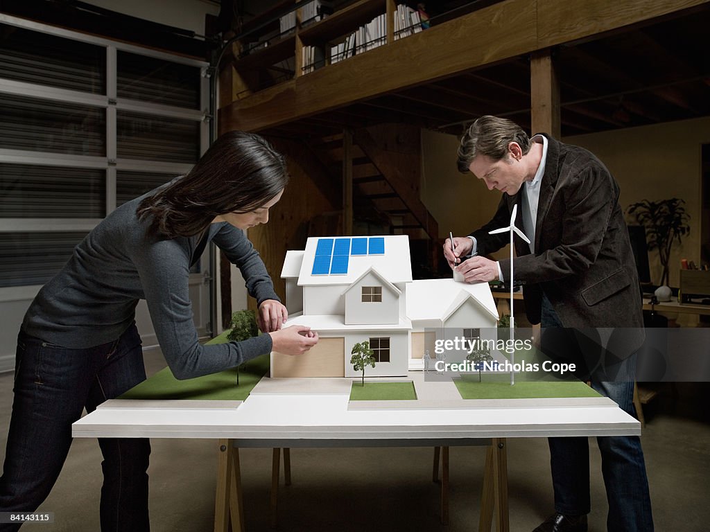 Man and woman make tweaks on architectural model.