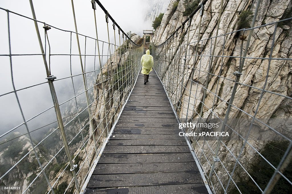A man walks across a suspension foot bridge