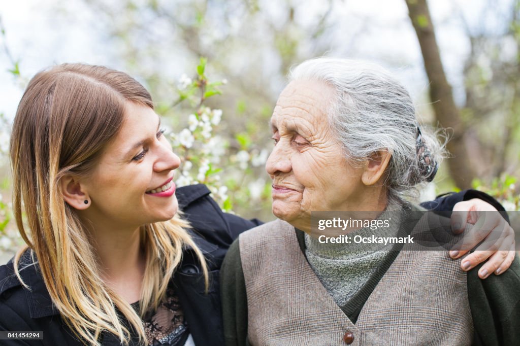 Happy elderly woman with carer outdoor - springtime