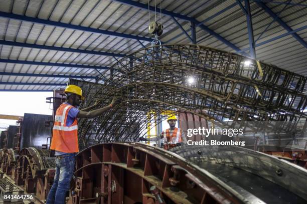 Workers guide the steel reinforcing frame of a precast concrete tunnel segment being maneuvered by crane to a mold at the Mumbai Metro Rail Corp....